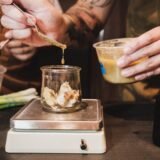 Bucătar care cântărește ingredientele pe un cântar digital, lângă o fișă tehnică de rețetă