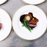 Raft cu sticle de vin într-un restaurant mic, lângă mese aranjate pentru cină