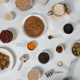 Boluri de lemn cu fasole albă, linte roșie și năut uscat, așezate pe o masă rustică de bucătărie