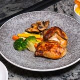 Meniu de prânz servit pe o masă de restaurant, cu un bol de ciorbă, un fel principal și pâine